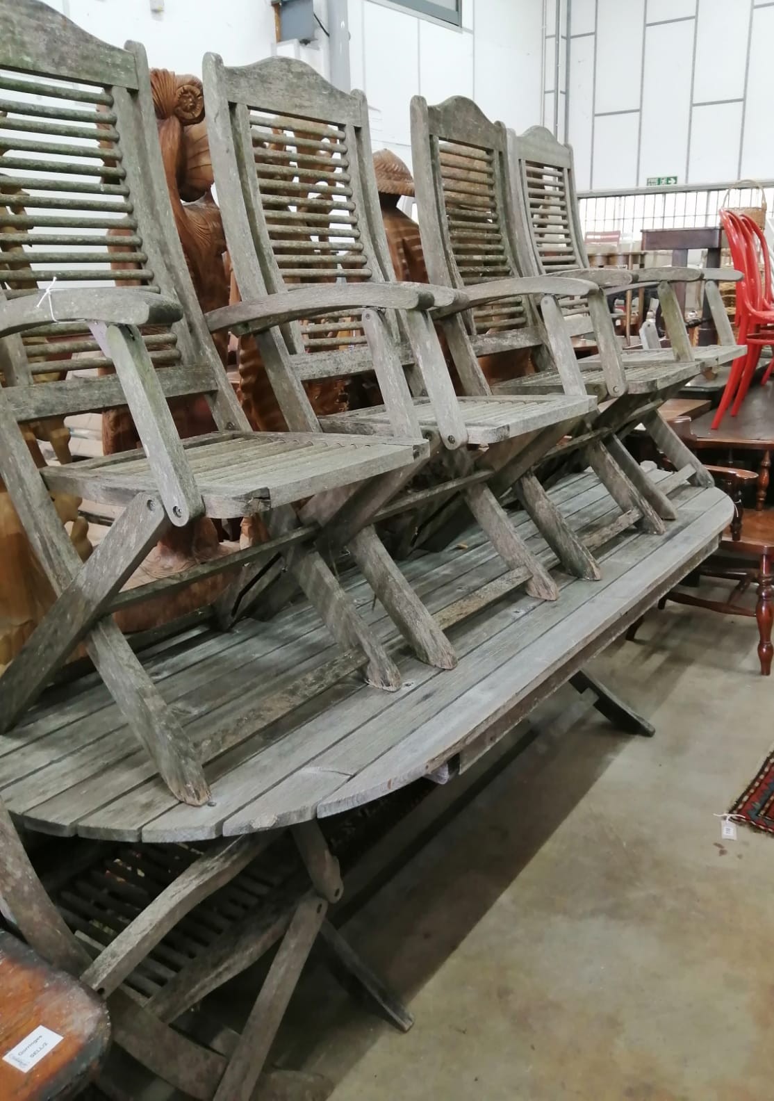 A weathered teak folding garden table, length 240cm, depth 100cm, height 69cm and five folding elbow chairs, labelled 'Firman' *Please note the sale commences at 9am.